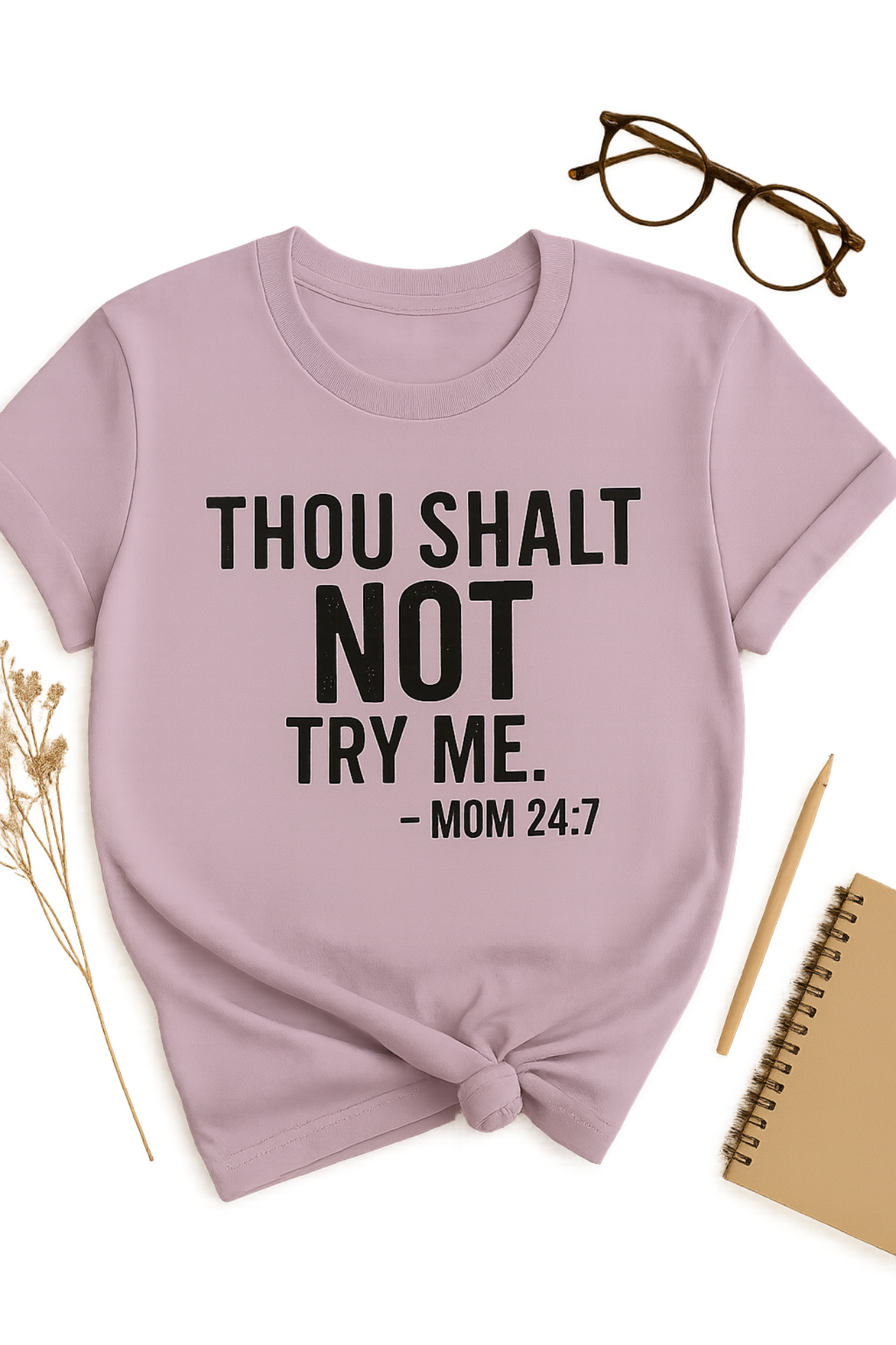 Lavender t-shirt with text 'THOU SHALT NOT TRY ME. - MOM 24:7' on a white background with glasses, pen, and notebook.